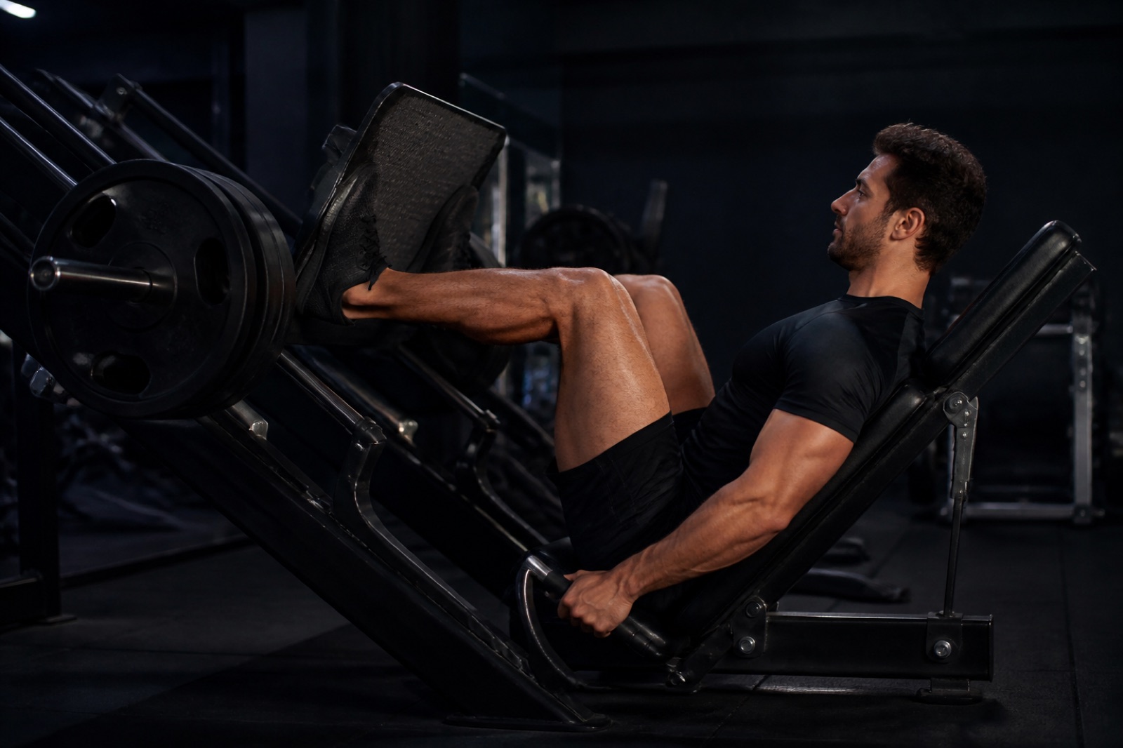Person som utför benpress i en maskin i ett gym, sedd från sidan