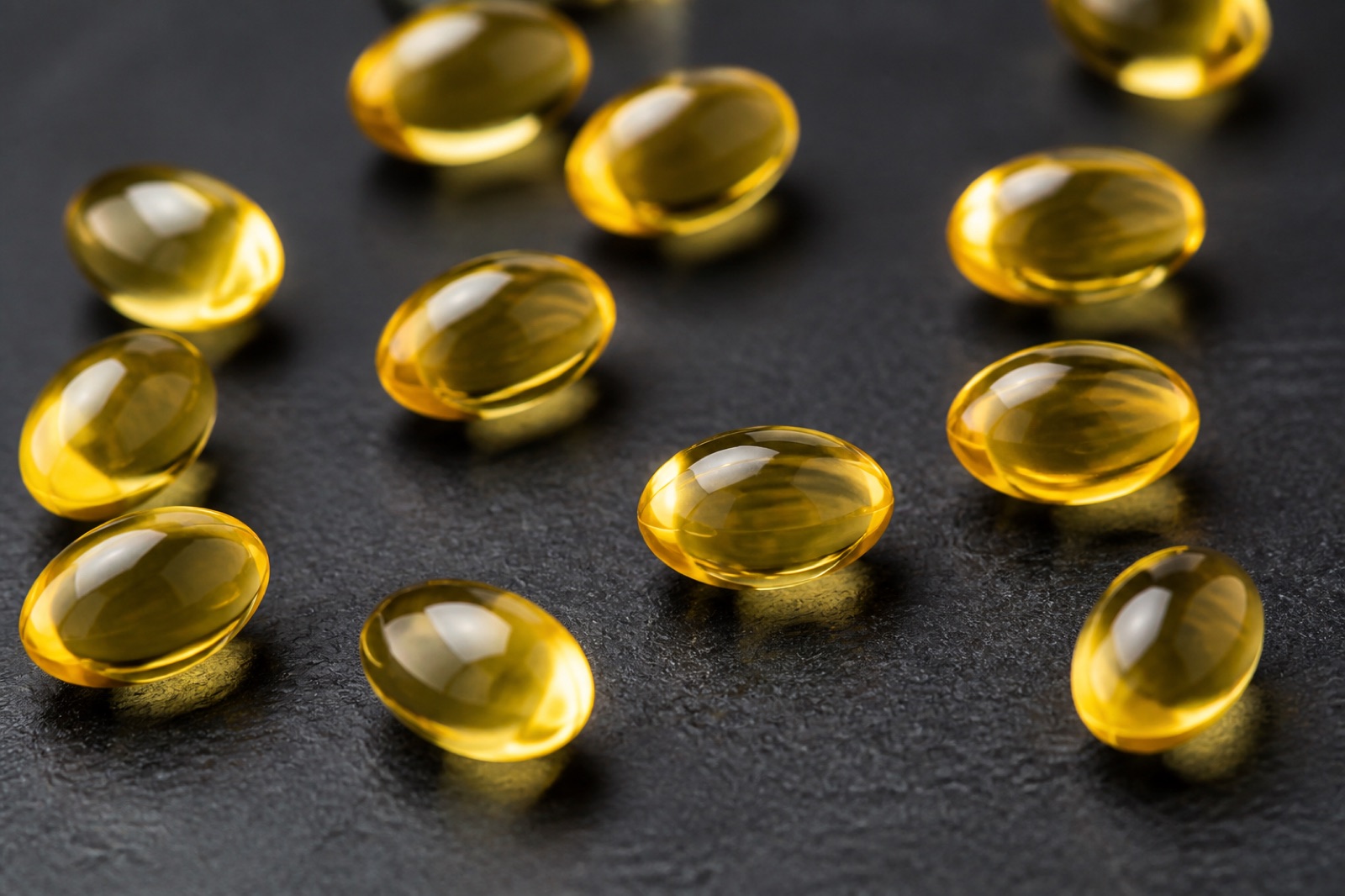 Gula D-vitaminkapslar på en mörk bänkskiva