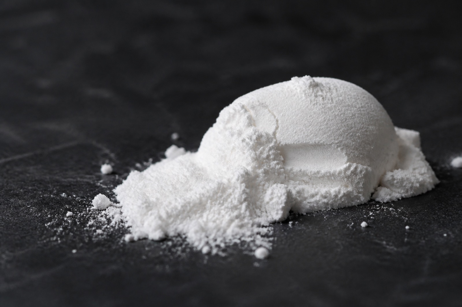 Vitt aminosyrapulver i ett mått på en mörk bänkskiva