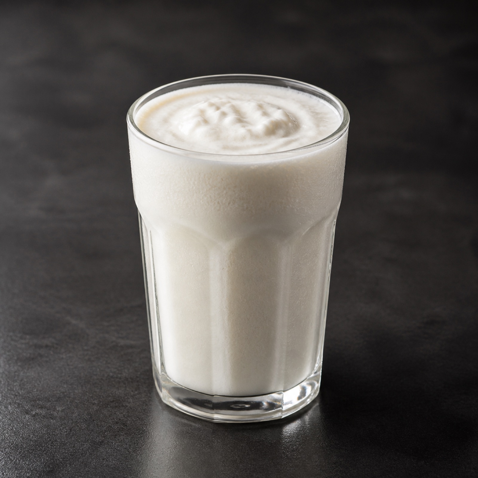 Krämig kaseinshake i ett glas på en mörk bänkskiva