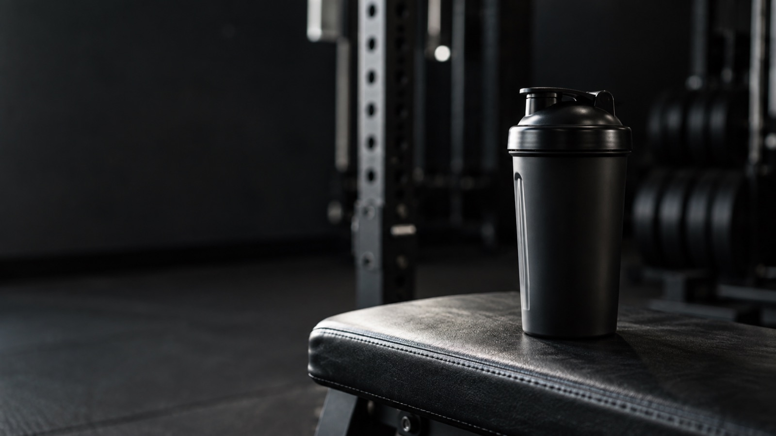 Svart proteinshaker på en mörk bänk i ett gym